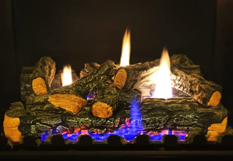 A gas fireplace with artificial logs shows orange-yellow and blue flames against a dark background, creating a warm and cozy atmosphere—perfect for relaxing evenings in Nashville after a chimney sweep.